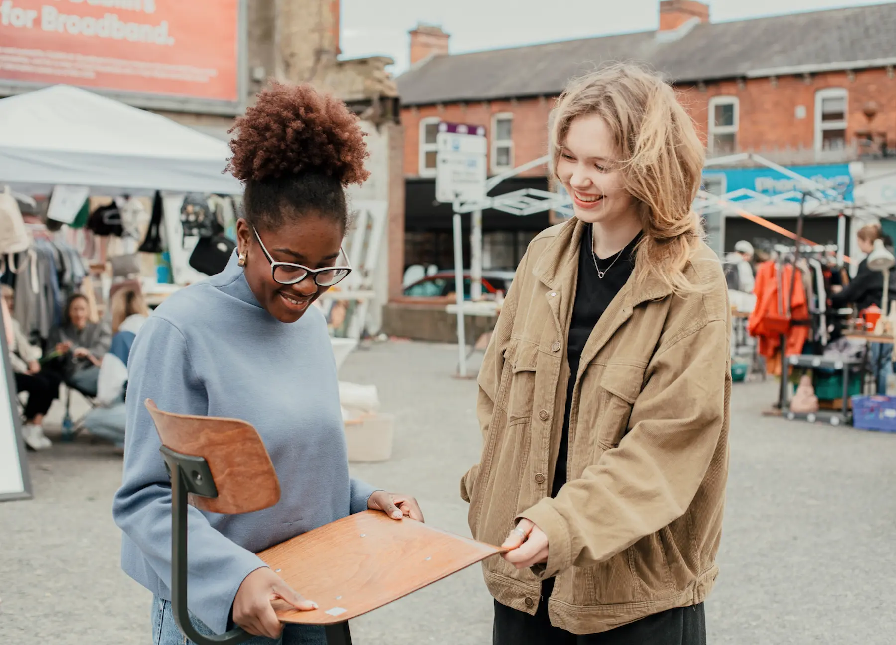 Two women investigate a chair bought from a flea market visible in the background.